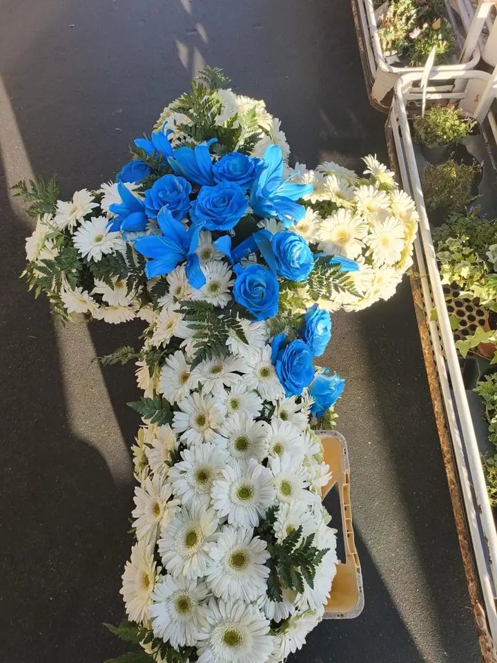 Croix florale blanche et bleu vif avec feuillage vert